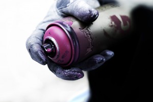 Photograph of a hand holding a graffiti spray paint can.